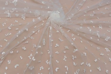 Doku danteli kumaş. Beyaz arka plan stüdyosunda dantel. İplik ya da iplikten yapılmış ince kumaş. Fildişi renkli dantel kumaşın arkaplan resmi. Bej arkaplanda beyaz dantel.