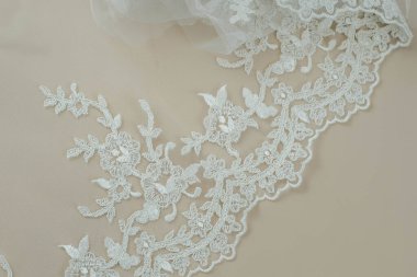 Doku danteli kumaş. Beyaz arka plan stüdyosunda dantel. İplik ya da iplikten yapılmış ince kumaş. Fildişi renkli dantel kumaşın arkaplan resmi. Bej arkaplanda beyaz dantel.