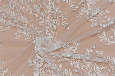 Doku danteli kumaş. Beyaz arka plan stüdyosunda dantel. İplik ya da iplikten yapılmış ince kumaş. Fildişi renkli dantel kumaşın arkaplan resmi. Bej arkaplanda beyaz dantel.