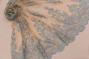 Doku danteli kumaş. Beyaz arka plan stüdyosunda dantel. İplik ya da iplikten yapılmış ince kumaş. Fildişi renkli dantel kumaşın arkaplan resmi. Bej arkaplanda gri dantel.