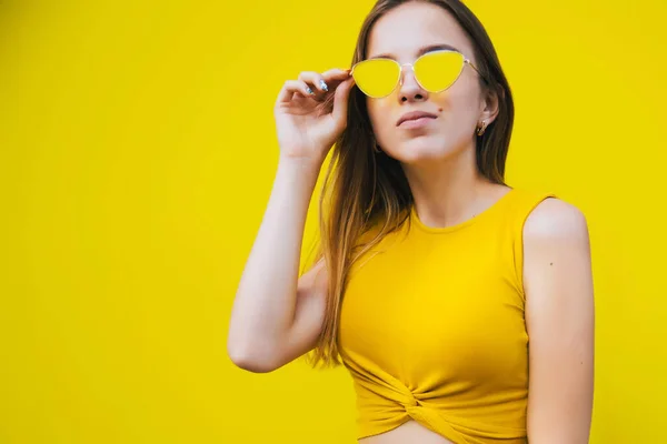 Retrato de una linda adolescente con ropa amarilla y gafas de sol amarillas sobre fondo amarillo . —  Fotos de Stock