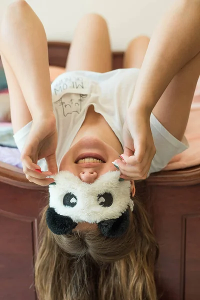 Cute teenage girl in her bed in pajamas and sleep mask panda. — ストック写真