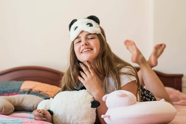 Cute teenage girl in her bed in pajamas and sleep mask panda. — ストック写真