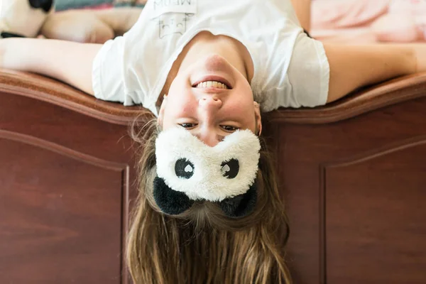 Cute teenage girl in her bed in pajamas and sleep mask panda. — Stockfoto