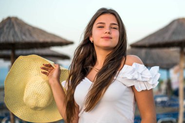Sahilden keyif alan, şapkalı, neşeli ve cüsseli bir genç kızın portresi. Gülümseyen, mutlu, pozitif duygu, yaz tarzı.