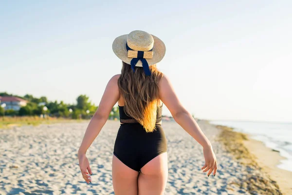 Parte de trás da menina adolescente alegre plus size usando chapéu apreciando a praia. sorrindo, feliz, emoção positiva, estilo de verão . — Fotografia de Stock