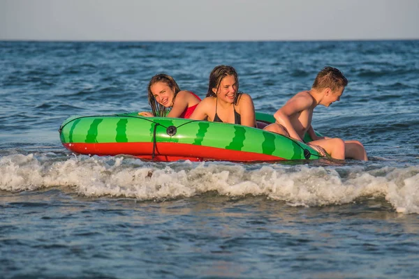 Happy friends two teenage girls and boy floating with watermelon lilos, sea - Young trendy people having fun swimming in summer vacation - Youth lifestyle, travel and party concept — ストック写真