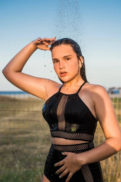 Beautiful young woman taking relaxing shower on sunny day, outdoors. Close up portrait. Sunny day. Tropical holidays getaway. Water flows through the body of the girl.Water splashing. — 스톡 사진