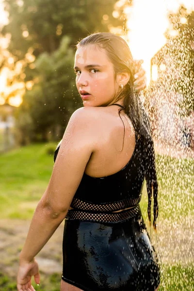 Mulher bonita tomando banho relaxante no dia ensolarado, ao ar livre. Fecha o retrato. Dia ensolarado. Férias tropicais escapam. A água flui através do corpo da menina.Água salpicando . — Fotografia de Stock