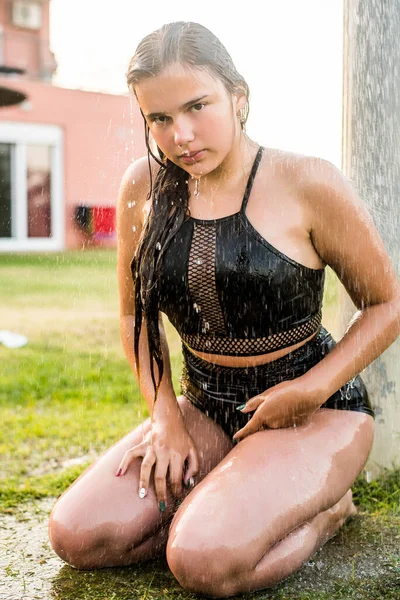 Gyönyörű fiatal nő vesz pihentető zuhany a napsütéses napon, a szabadban. Csukd be a képet. Napsütéses nap. Trópusi nyaralás. Víz folyik keresztül a test a lány.Víz fröccsenő. — Stock Fotó