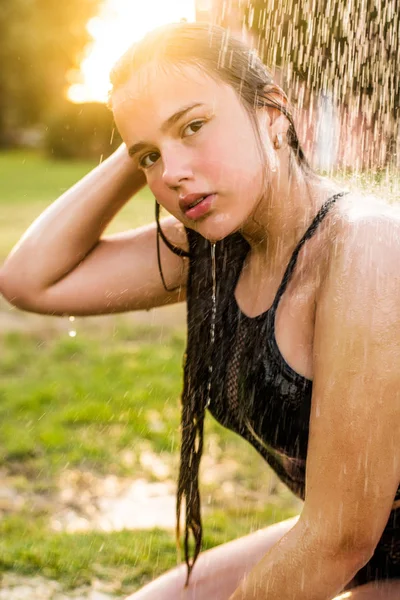 Красивая молодая женщина принимает расслабляющий душ в солнечный день, на открытом воздухе. Закрыть портрет. Солнечный день. Тропические каникулы. Вода плавает по телу девушки. . — стоковое фото