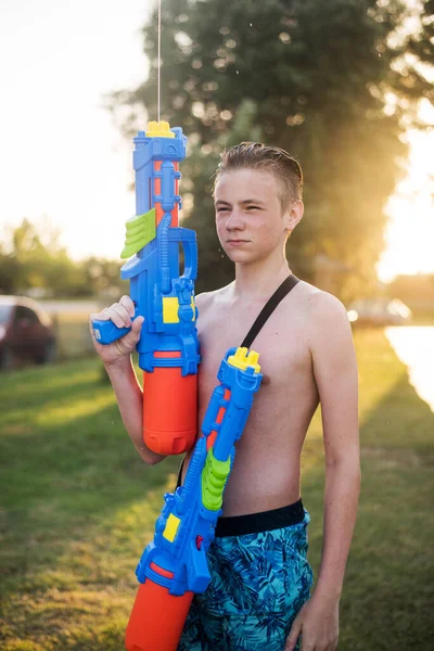 Retrato de un lindo adolescente con dos pistolas de agua o pistolas. Feliz concepto de vacaciones de verano . — Foto de Stock