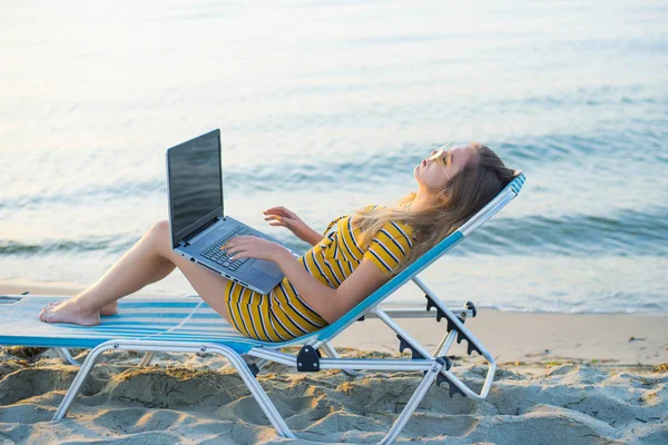 Mujer joven usando un ordenador portátil en una playa. Concepto de trabajo independiente — Foto de Stock