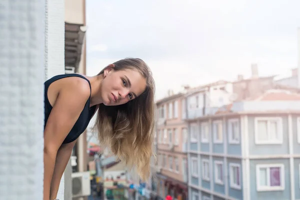 Close-up portrait of cute teenage girl on city background. Lovable lady standing near window and looking at beautiful building. — Stok fotoğraf