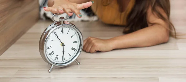 Sleepy young woman trying kill alarm clock . Early wake up, not getting enough sleep, getting work concept. Female stretching hand to ringing alarm willing turn it off