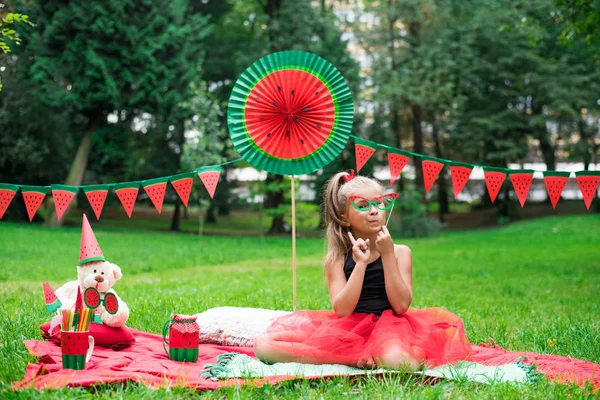 Görögdinnyés buli, piknik gyerekeknek a parkban. Görögdinnye nap. Aranyos kislány szemüveggel. — Stock Fotó