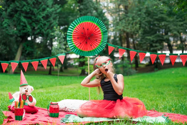 Fiesta de sandía, picnic para niños en el parque. Día de sandía. Linda niña pequeña con gafas. — Foto de Stock