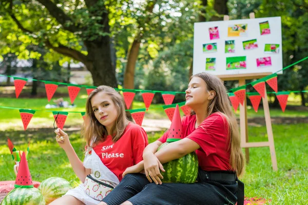 Two nice teen girls having fun eating watermelon In the park. Excellent sunny weather. Summer concept. Watermelon party, picnic, day — ストック写真