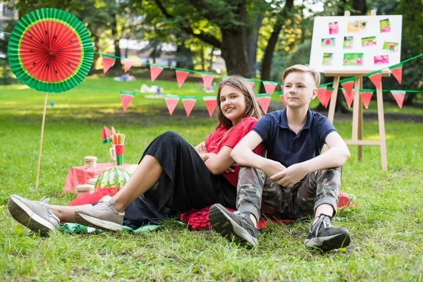 Nice teen girl and boy having fun watermelon party In the park. Excellent sunny weather. Summer concept. Watermelon party, picnic, day. — ストック写真