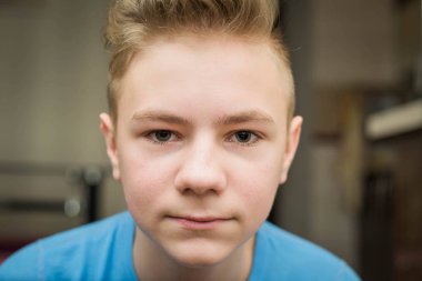 Close up portrait of a young teenager man looking at camera with a joyful smiling expression, against a background at home, interior. Teenager being confident and smart, indoors.