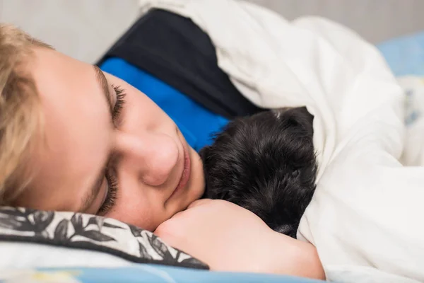 Lindo adolescente durmiendo con schnauzer en miniatura negro. Abrazando, amor, concepto de cuidado —  Fotos de Stock