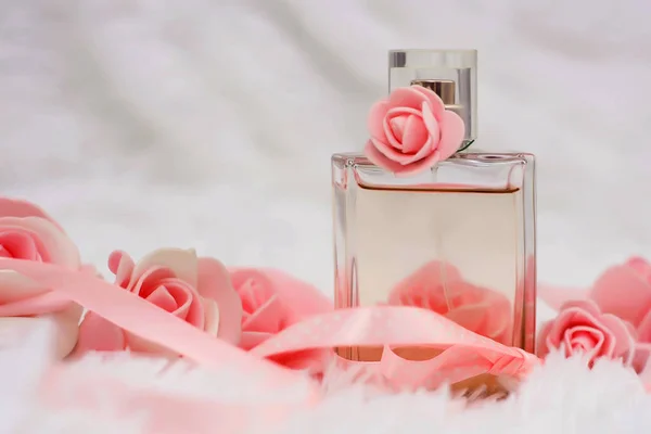 Botella de perfume con flores sobre fondo blanco esponjoso. color del año 2019 Pantone - Living Coral . —  Fotos de Stock