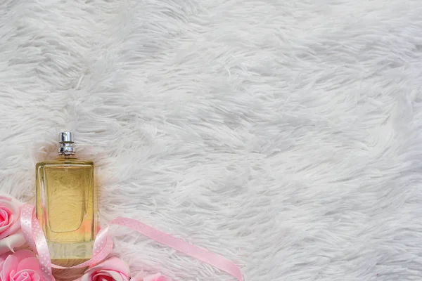 Egy üveg parfüm fehér, bolyhos hátterű virágokkal. lapos fekvés, felülnézet, másolás, szabad hely a szövegnek. — Stock Fotó
