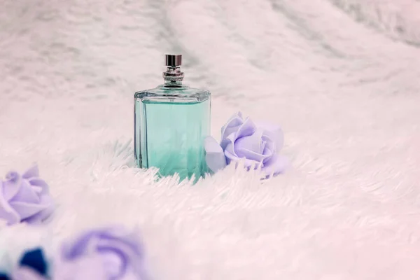 Garrafa de perfume com flores em fundo macio branco — Fotografia de Stock