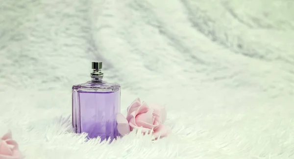 Garrafa de perfume com flores em fundo macio branco — Fotografia de Stock