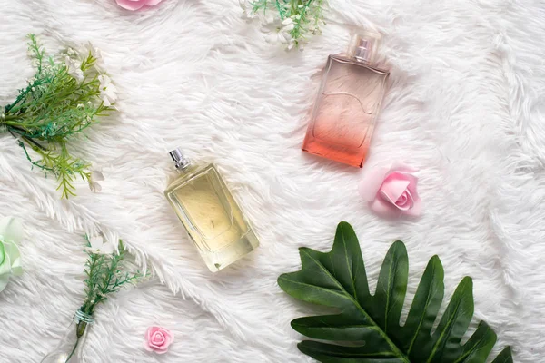 Bottles of perfume with flowers on white fluffy background. flat lay, top view — Stock Photo, Image