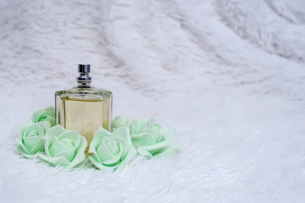 Пляшка парфумів з квітами на білому пухнастому фоні — стокове фото