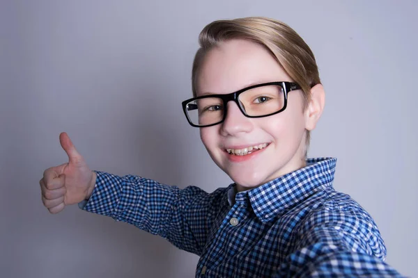 Back to school. Funny teenage boy in glasses pointing up on gray background. Child from elementary school. Education. Clever happy kid — Stock Photo, Image