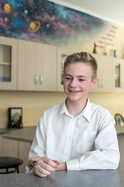 Back to school and happy time. Cute teenage boy is sitting at a desk indoors. Student is learning in class — Stock Photo, Image