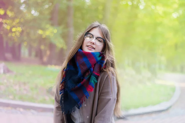 Porträtt av en vacker flicka i parken. Tonårsflicka med färgglad scarf och brun päls. Närbild foto. Ung student ha kul. Livsstil foto. lycka koncept - leende flicka. — Stockfoto