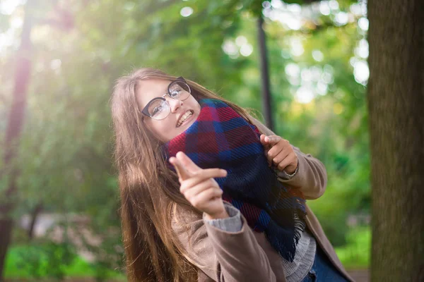 Retrato de uma menina bonita no parque. Menina adolescente com cachecol colorido e casaco marrom. Feche a foto. Jovem estudante se divertir. Foto de estilo de vida. conceito de felicidade - menina sorridente . — Fotografia de Stock