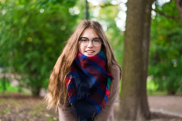 Porträt eines schönen Mädchens im Park. Teenager-Mädchen mit buntem Schal und braunem Mantel. Nahaufnahme Foto. Junge Studenten haben Spaß. Lifestyle-Foto. Glückskonzept - lächelndes Mädchen. — Stockfoto