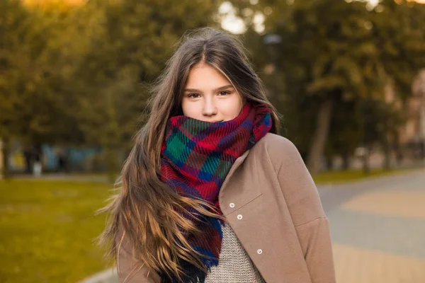 Porträt eines schönen Mädchens im Park. Teenager-Mädchen mit buntem Schal und braunem Mantel. Nahaufnahme Foto. Junge Studenten haben Spaß. Lifestyle-Foto. schönes Haar. — Stockfoto