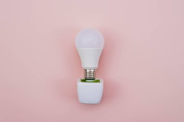 Esrarlı LED lamba, ECO enerji konsepti, yakın çekim. Pembe arka planda ampul. Enerji ve Ekolojik Çevre Kaydediliyor.