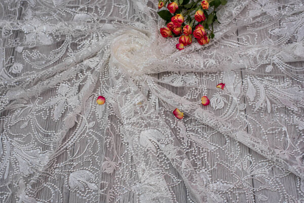 White wooden background with white spring flowers roses and lace ribbon. Happy womans day. The texture of lace on wooden background.