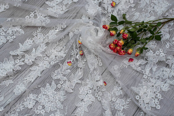 White wooden background with white spring flowers roses and lace ribbon. Happy womans day. The texture of lace on wooden background.
