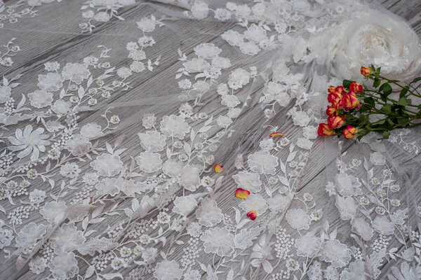 White wooden background with white spring flowers roses and lace ribbon. Happy womans day. The texture of lace on wooden background.