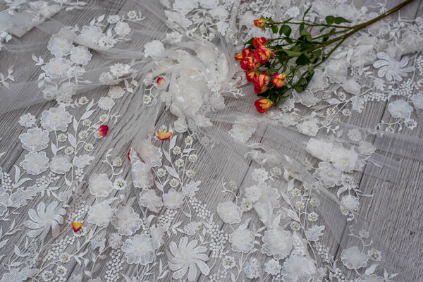 White wooden background with white spring flowers roses and lace ribbon. Happy womans day. The texture of lace on wooden background.