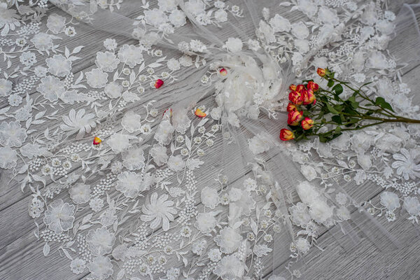 White wooden background with white spring flowers roses and lace ribbon. Happy womans day. The texture of lace on wooden background.