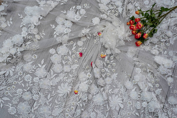 White wooden background with white spring flowers roses and lace ribbon. Happy womans day. The texture of lace on wooden background.