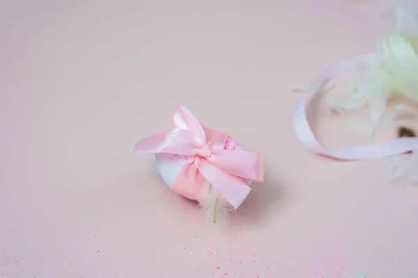 Easter egg with a pink bow on pink background. Copy space.