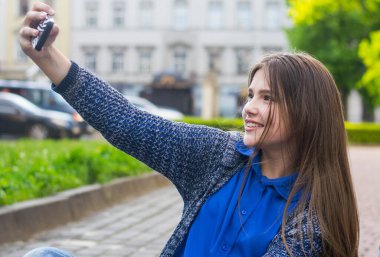 Güzel bir genç kız, güzel bir havada parkta yürüyüş için selfie çeker..
