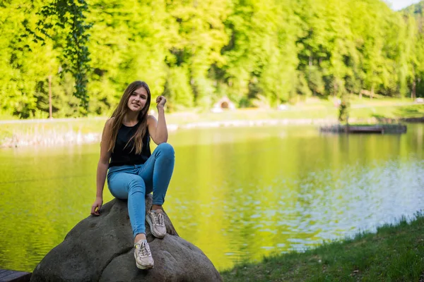 Shy girl sanding looking at camera . Cute teenage girl being shy on lake background