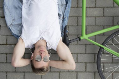 Bisikletli bir adam asfaltta yatıyor ve ata bindikten sonra rahatlıyor. Aktif yaşam tarzı. Bahar güneşli kavram.