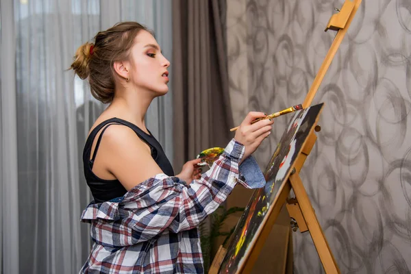創造的な幸せな画家はカラフルな絵を描く 肯定的な女性画家の笑顔は彼女のスタジオでペイントします 十代の女の子 — ストック写真