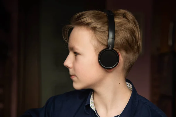 Distance Learning, Home-based Learning. A boy in headphones in front of a computer does his homework